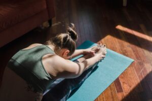 A lady practicing Yoga on a Mat in a indoor environment